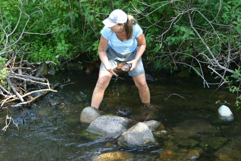woman removing rock from spring